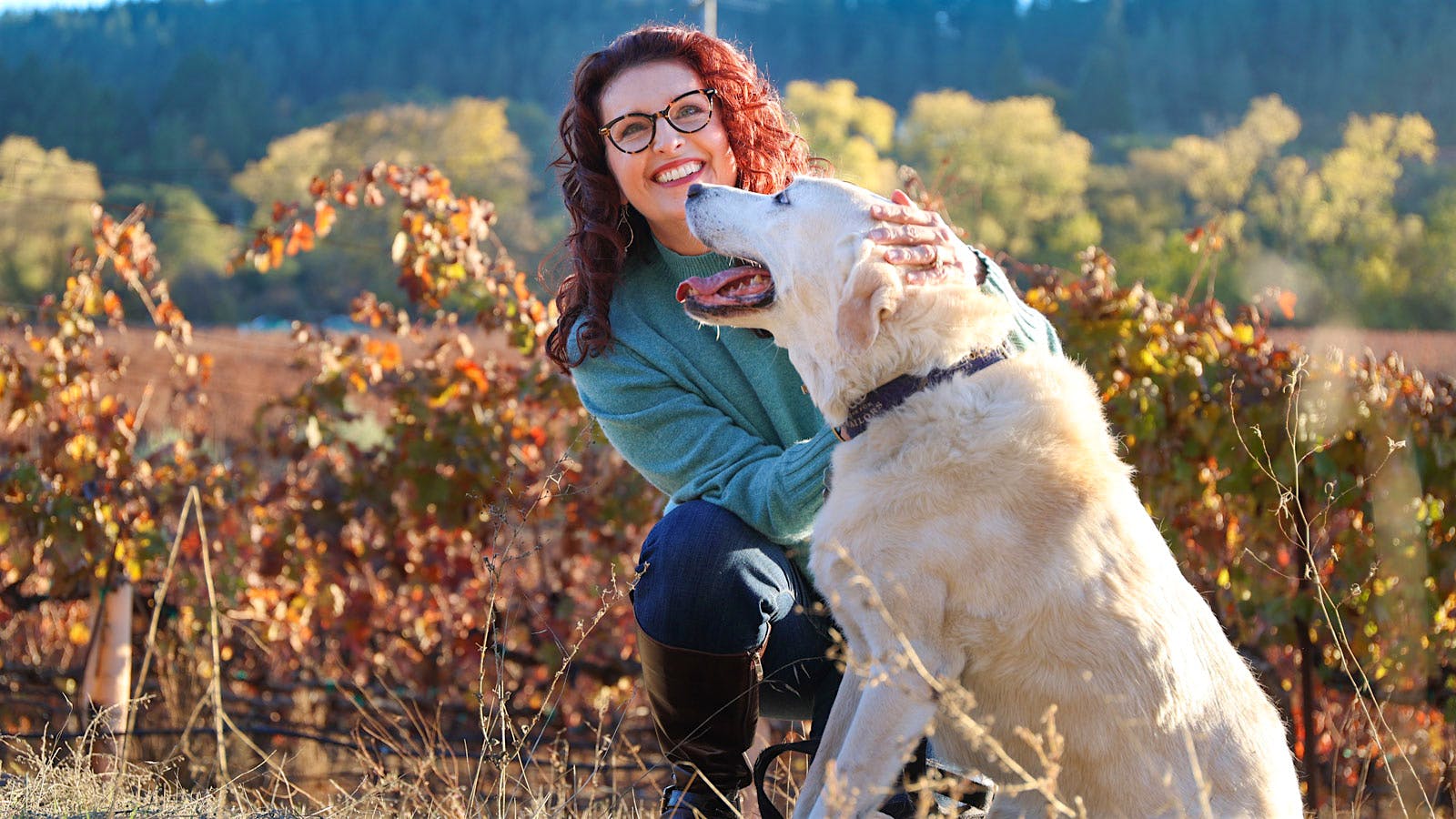 Portrait of vintner Kim Stare Wallace in a vineyard with her Yellow Labrador, Holly