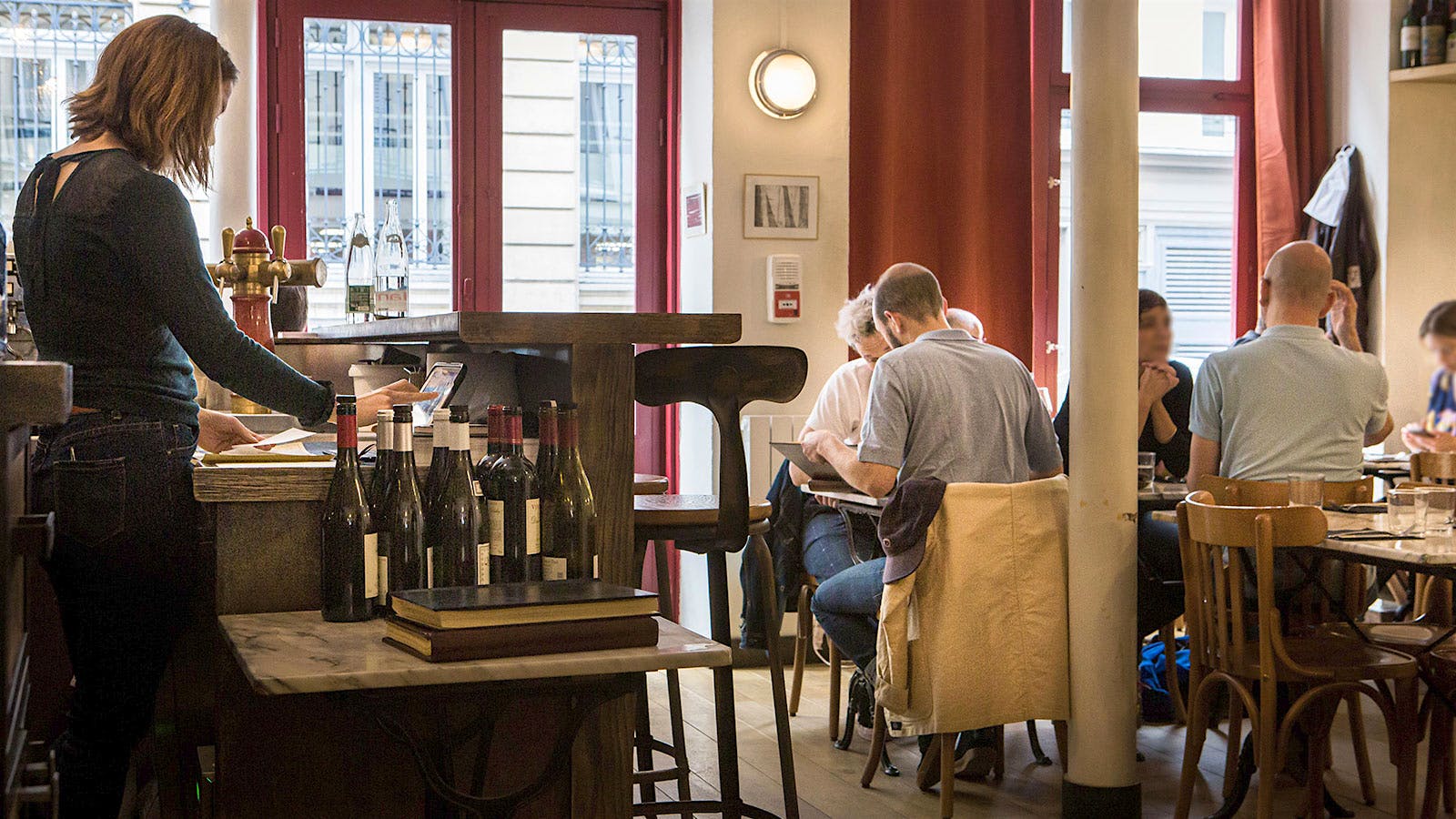 The dining room of Vantre, with guests eating and servers with bottles of wine